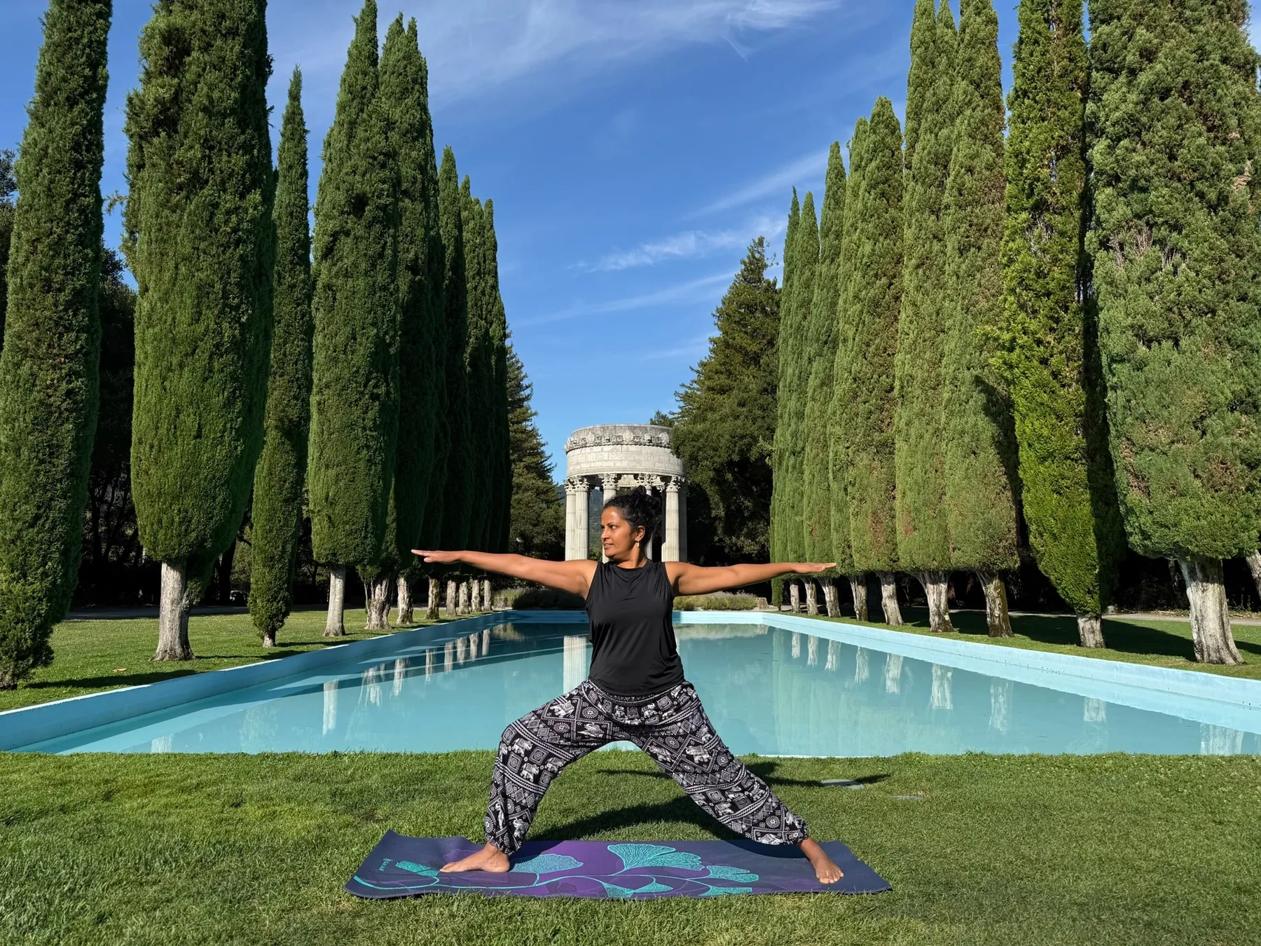 Pushya practicing yoga outdoors beside a reflecting pool